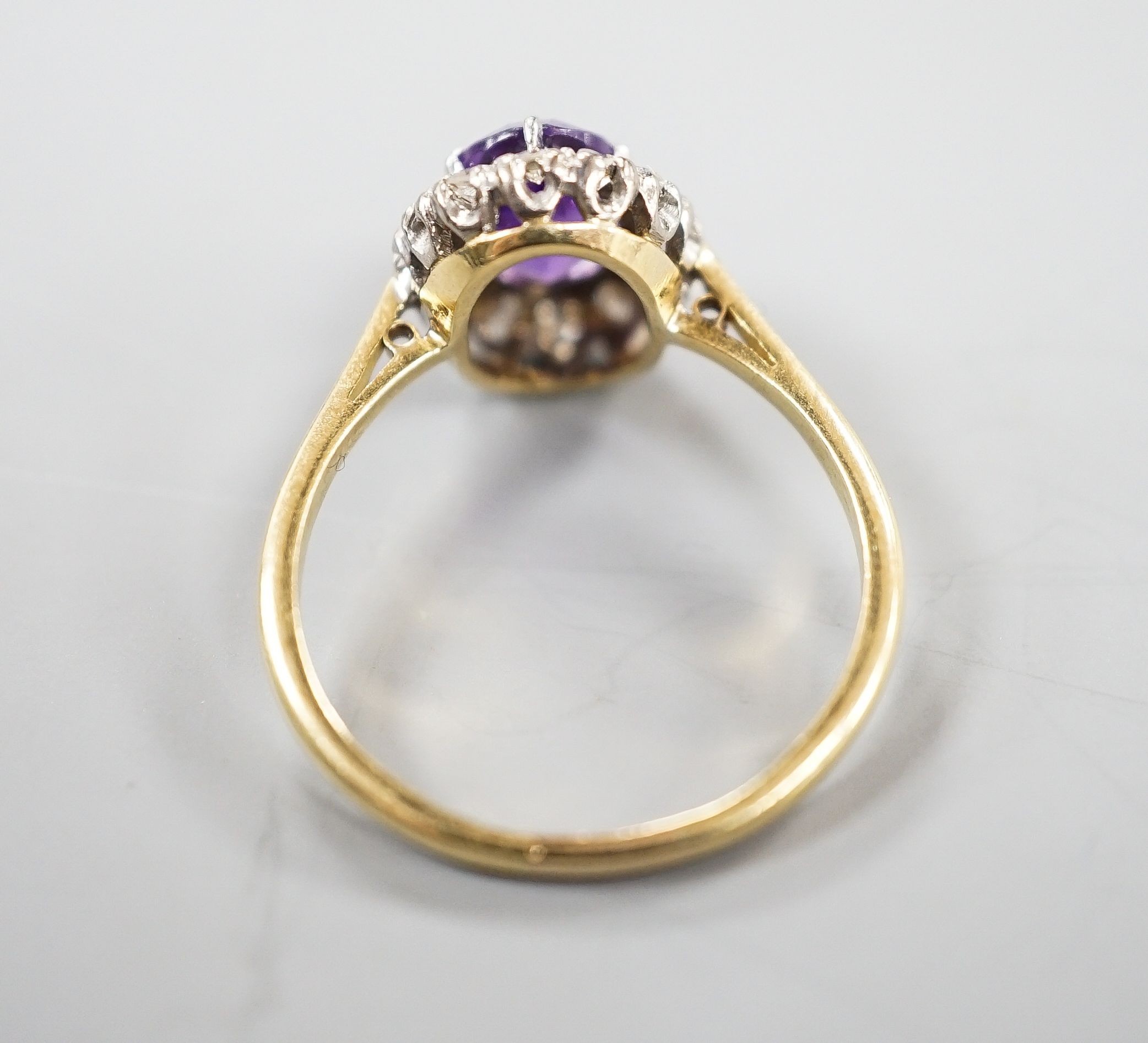 An 18ct, amethyst and diamond set oval cluster ring, size O/P, gross weight 3 grams.